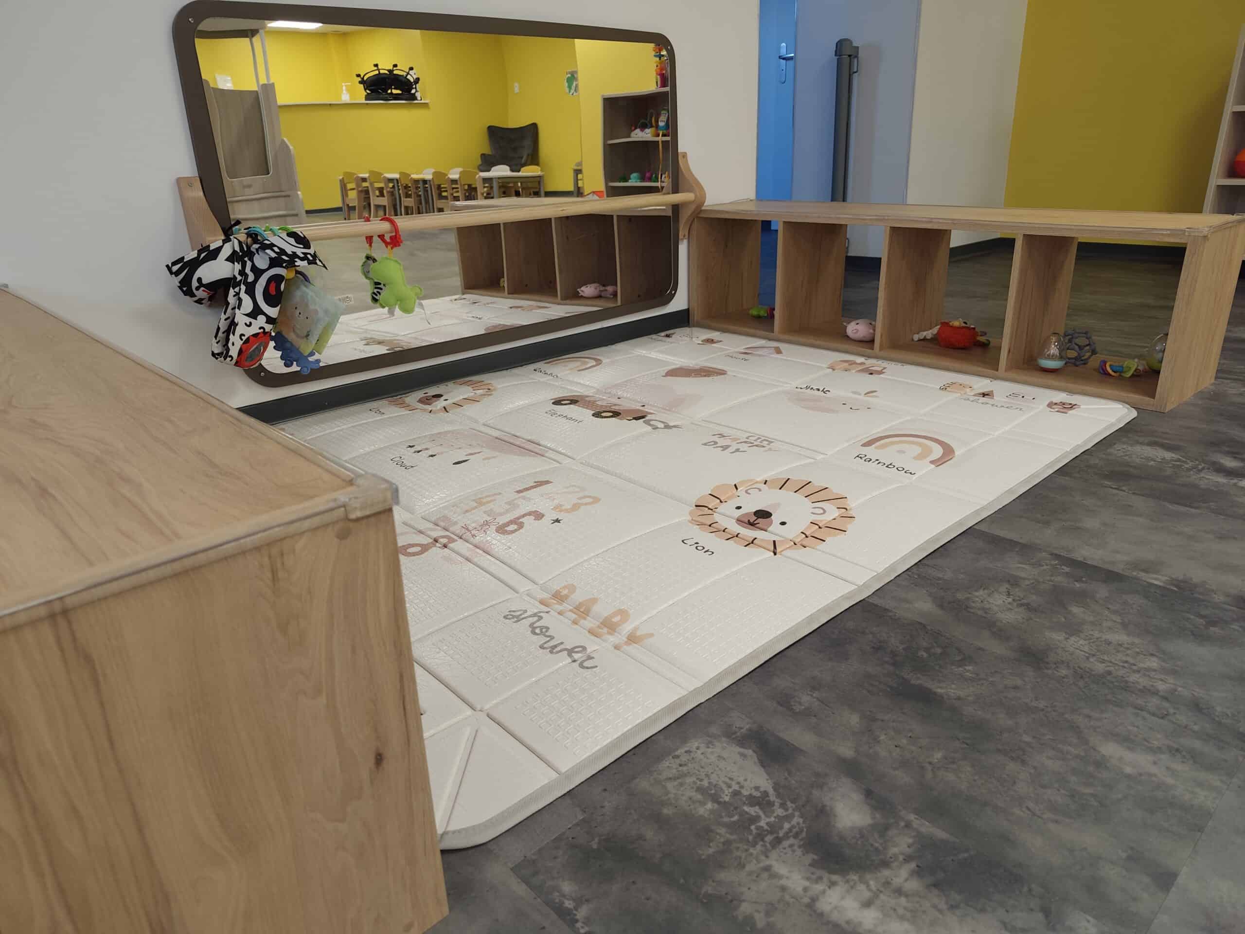Espace de motricité avec tapis, miroir et mobilier adapté aux jeunes enfants